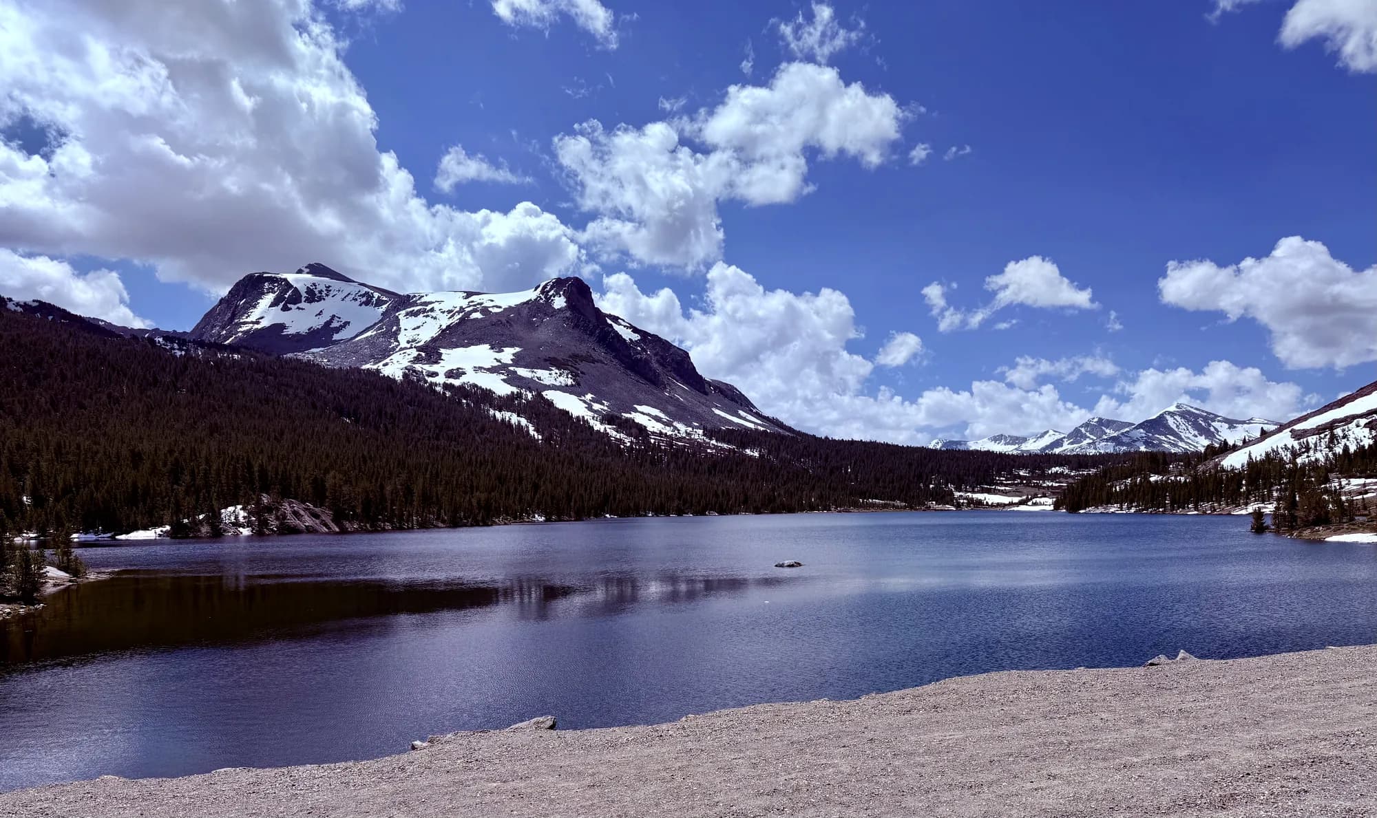 An alpine Sierra lake with granite slopes and pines reflected in still water. No people are shown.