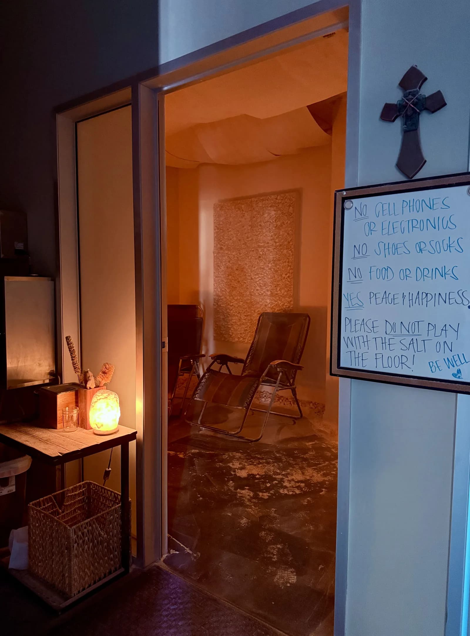 Warm entrance to a Himalayan salt suite, with a glowing salt-brick wall, lounge chairs, and a wooden bench. No people are shown.